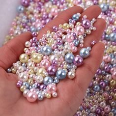 a hand holding a bunch of multicolored pearls