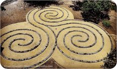 an aerial view of a garden with spirals in the ground and trees around it