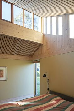 a bed sitting under a wooden ceiling next to a window