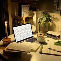 an open laptop computer sitting on top of a wooden table next to books and papers