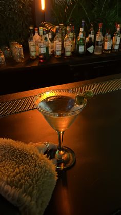 a martini sitting on top of a bar next to bottles