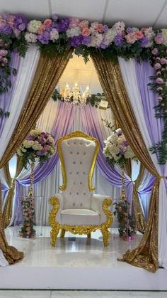 a chair sitting in the middle of a stage decorated with flowers and gold trimmings