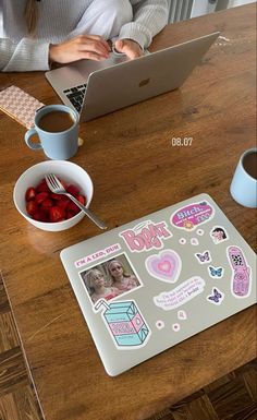 a woman sitting at a table with a laptop and some fruit in front of her