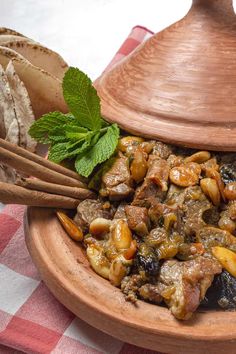 a wooden bowl filled with meat and vegetables on top of a checkered table cloth