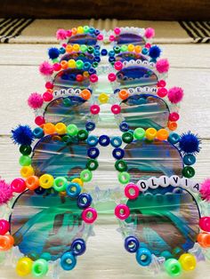 many colorful sunglasses are lined up on a table with pom - poms around them