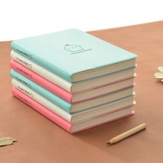 a stack of four notebooks sitting on top of a table next to a flower