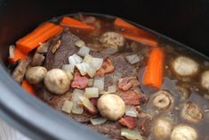 meat, carrots and mushrooms are being cooked in the crock pot with broth