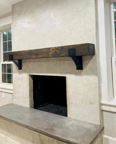 a fireplace in a living room with white walls and wood trimming on the mantle