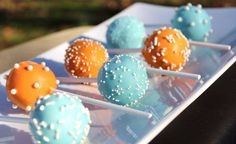 some cake pops with sprinkles and blue and orange frosting on them