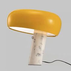 a yellow table lamp sitting on top of a white floor next to a black cord