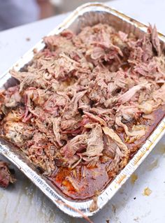 an uncooked casserole dish with meat and sauce in it sitting on a table