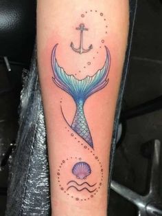 an anchor and mermaid tail tattoo on the arm