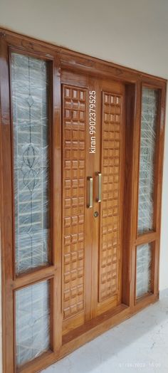 two wooden doors with glass panels on each side and one has a name written on it