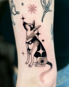 a small dog tattoo on the right leg with stars and butterflies in the sky above it