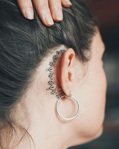 a woman with a tattoo on her left ear and behind the ear is a circular ring