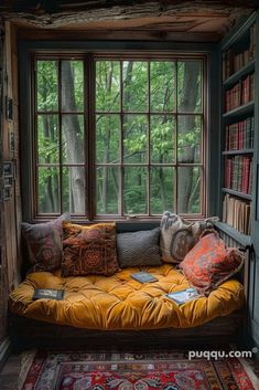 a window seat in the corner of a room with bookshelves and rugs