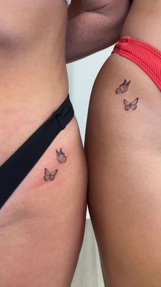 two women's butts with small butterflies on their thighs, one is black and the other is white