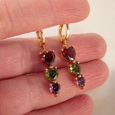 Beautiful Women's "Trilogy Design" Multi Color Heart Shape Zircon Dangle Party Earrings 18k Yellow Gold Filled W/ Heart Shape Garnet Red, Peridot Green, + Amethyst Purple Simulated Diamond Topaz Zircon Gemstones. Top Quality, High Polished Shine, Brand New, Never Been Worn. Lead, Nickel Free. These Gorgeous Earrings Sparkle. The "Trilogy" Design Represents Different Things To Different People - Past, Present, And Future, Relationships, Three Years Together, Three Special People. Perfect Jewelry Heart Diamond Earrings, Garnet Red, Color Heart, Crystal Jewelry Sets, Peridot Green, Zircon Jewelry, Heart Dangle Earrings, Gold Jewellery Design Necklaces, Sparkle Earrings