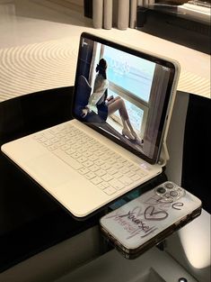 an open laptop computer sitting on top of a table next to a cell phone and tablet