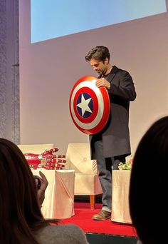 a man holding a captain america shield on stage