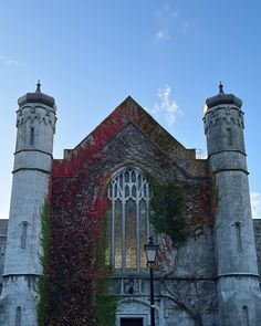 an old building with ivy growing on it's side and two tall towers in the background