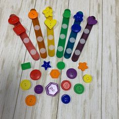 several different colored buttons are arranged in the shape of flowers and leaves on a white wooden surface