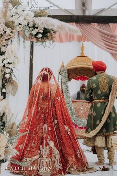 the bride is getting ready to walk down the aisle in her red and gold lehenga