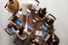 four people sitting at a table working on laptops