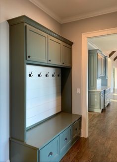 an entryway with a bench and cabinets in it, next to a hallway leading to another room