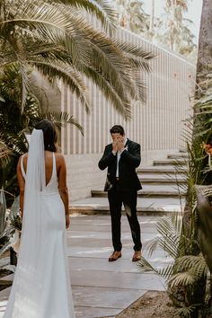 a man in a suit and tie standing next to a woman wearing a wedding dress