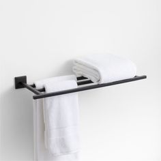 two white towels are hanging on a black towel rack in front of a white wall