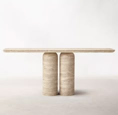 two concrete pillars stand in front of a white wall and the table is made out of cement