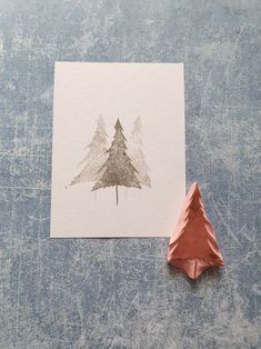 an origami christmas tree on a piece of paper next to a copper origami cone