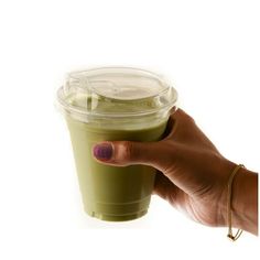 a woman's hand holding a green drink in a plastic cup with a straw