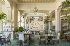 a dining room with tables and chairs in front of a large painting on the wall