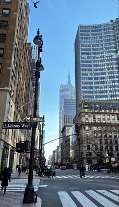 an empty city street with tall buildings in the back ground and people walking on the sidewalk