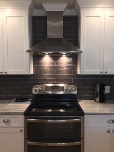 a stove top oven sitting inside of a kitchen next to white cabinets and counter tops