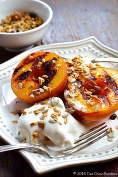 two peaches with yogurt and granola on a plate