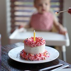 a small child in a highchair eating cake with a candle on the top