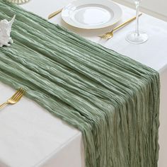 the table is set with green linens and gold place settings, including silverware