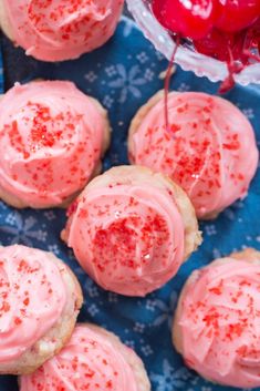 strawberry shortbreads with pink frosting and sprinkles on a blue napkin