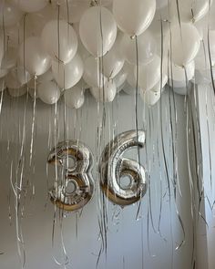 balloons and streamers are hanging from the ceiling with the number sixty six on them