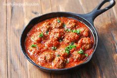 a skillet filled with meatballs on top of a wooden table