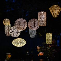 many lights are hanging from the ceiling above a table with flowers and candles on it