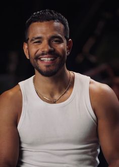 a man smiling and wearing a white tank top