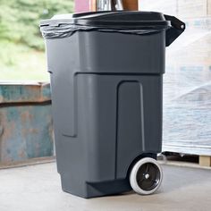 a large gray trash can sitting on top of a wooden floor next to a window