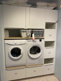 a washer and dryer in a room with shelves on the wall behind them