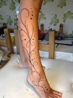 a woman's foot with an artistic tattoo design on her left leg and the bottom part of her body