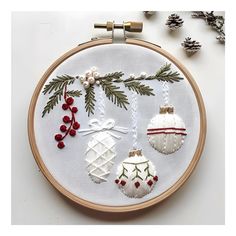 an embroidered christmas ornament with pine cones and baubles