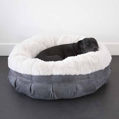 a black dog laying in a grey and white pet bed